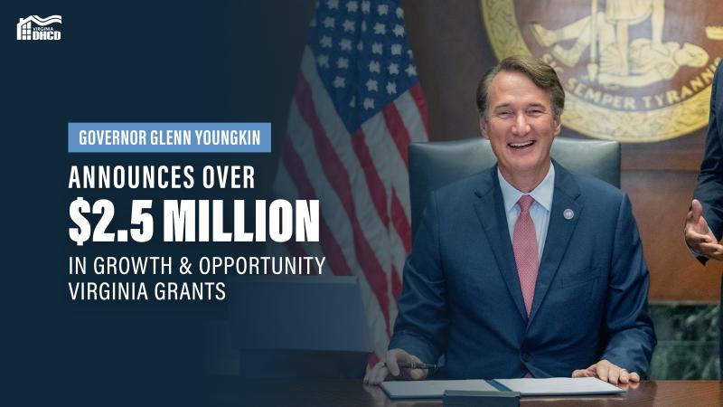 Una foto del gobernador Glenn Youngkin con traje azul y corbata roja, sonriendo a la cámara a punto de firmar una legislación; el texto blanco dice: El gobernador Glenn Youngkin anuncia más de $2.5 Millones en subvenciones para el crecimiento y las oportunidades en Virginia"